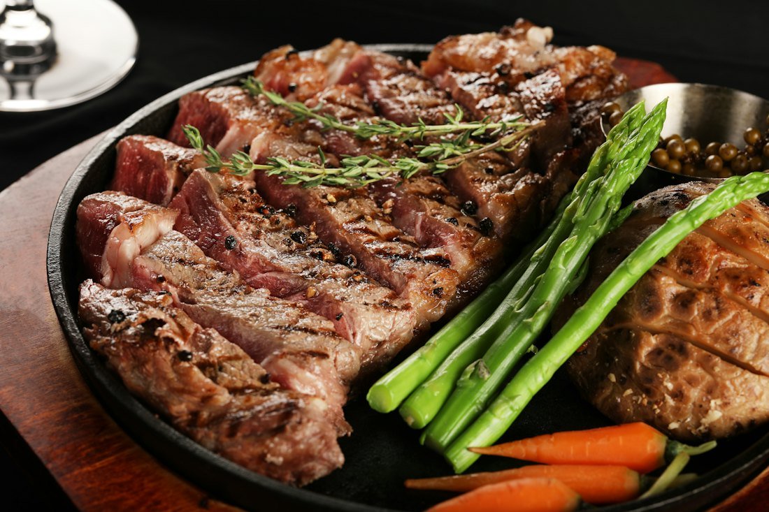 Raw beef cuts and a butcher knife on a wooden block